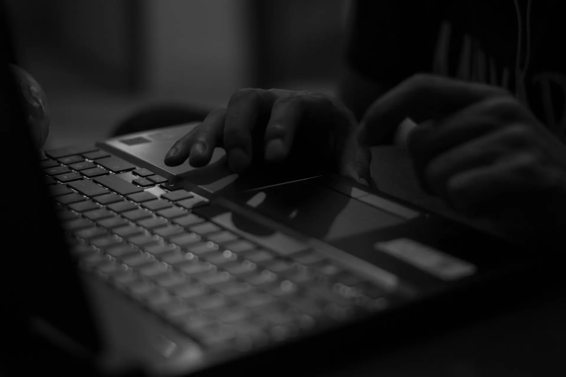 Hands typing on a laptop in low light
